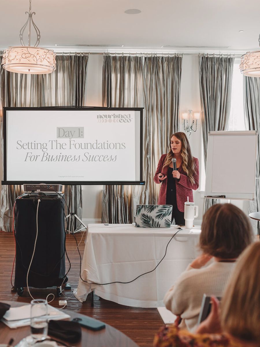 Business Coach Laura Schoenfeld in front of audience image for blog about How to Implement an Effective 90-day Business Planning Strategy